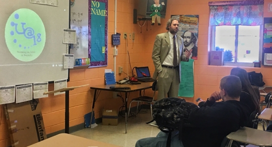 A teacher lecturing to students in a classroom.