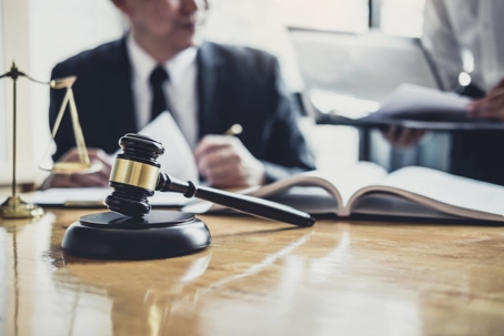 Legal representation, featuring a gavel and scales of justice on a wooden desk.